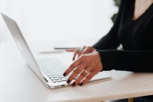 Une entrepreneure méconnaissable en tenue décontractée utilise un pavé tactile sur un ordinateur portable tout en travaillant à une table dans un bureau contemporain