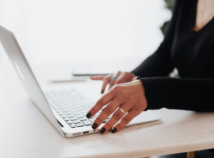 Une entrepreneure méconnaissable en tenue décontractée utilise un pavé tactile sur un ordinateur portable tout en travaillant à une table dans un bureau contemporain