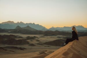 une femme assise au sommet d'une dune de sable