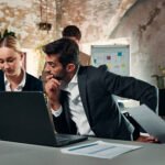 Team, laptop and advisor with business people in office for meeting, investment proposal and update. Broker planning, feedback and admin review with employees in finance agency for collaboration