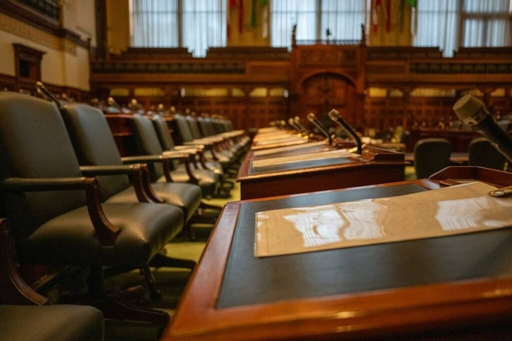 Salle de réunion avec des bureaux en bois, des chaises en cuir et des microphones