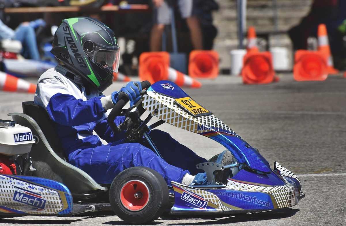 Un coureur en karting bleu sur circuit, portant casque et gants