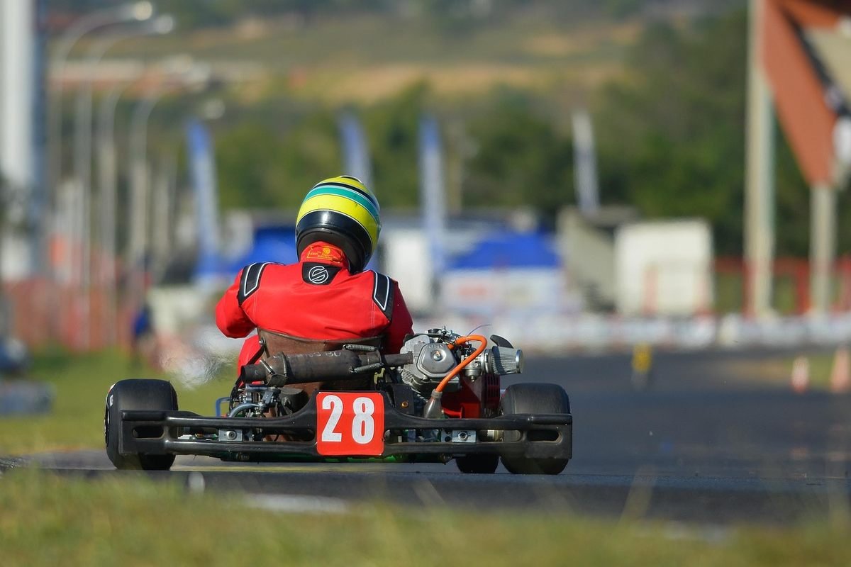Un coureur en combinaison rouge et casque pilote un kart