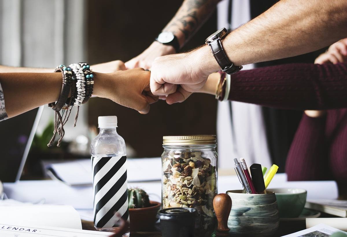 Des mains se rejoignent sur un bureau avec objets de travail Des mains se rejoignent sur un bureau avec objets de travail