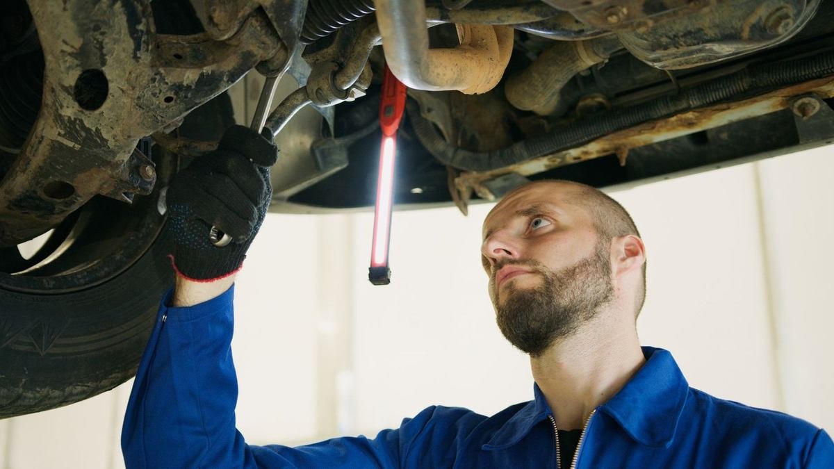 Mécanicien inspectant sous un véhicule avec des outils Mécanicien inspectant sous un véhicule avec des outils