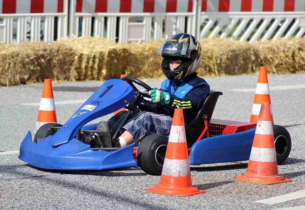 Un enfant pilote un kart bleu entre des cônes orange sur une piste Un enfant pilote un kart bleu entre des cônes orange sur une piste