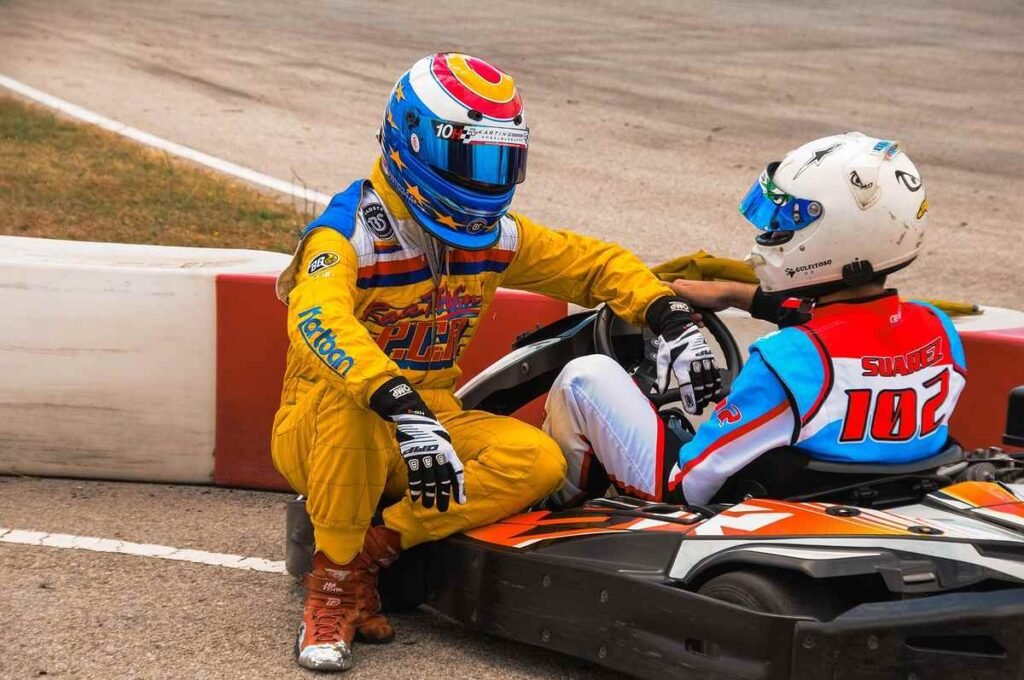 Un pilote en jaune aide un concurrent assis dans un kart rouge