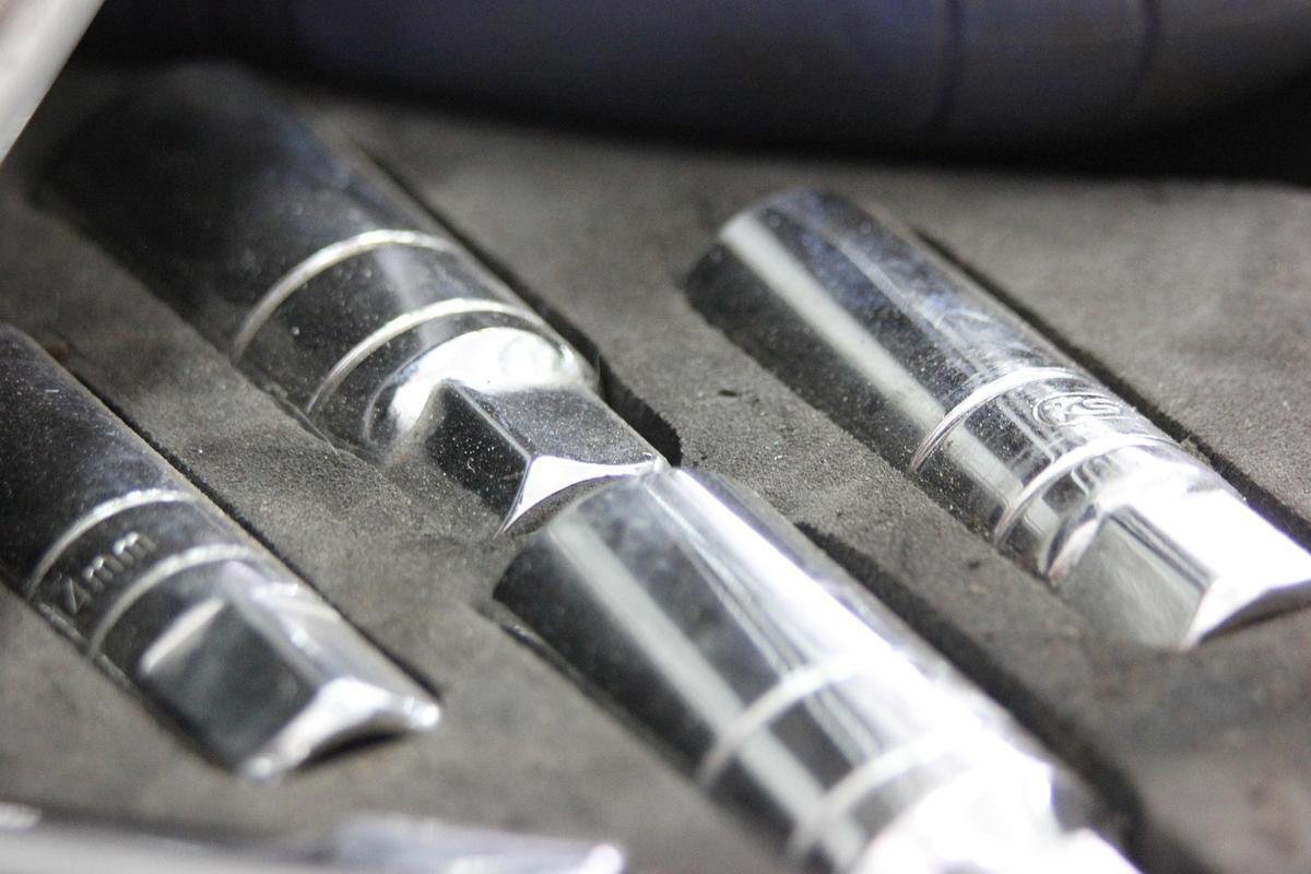 Outils en métal dans un étui gris, avec des têtes hexagonales et des marques de mesure
